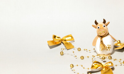 New Year Cow in Golden Decorated with Christmas Garland and Bow on a Gray background, New year of the bull, Space for Text, Copyspace, Gift Card
