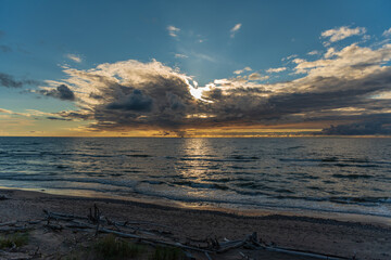 sunset behind the clouds close to the water horizon