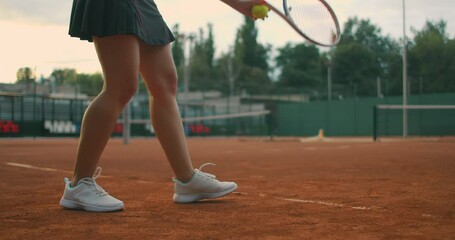 Slow motion close up: Young Caucasian teenager female tennis player serving during a game or...