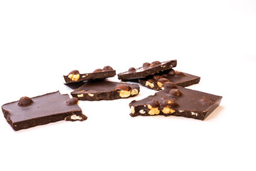 A few pieces of chocolate with a whole hazelnut on a white background