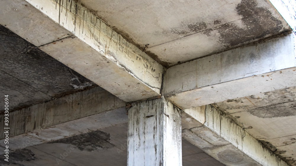 Poster old reinforced concrete floor with columns. mold and mildew on an abandoned building structure. cons