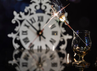 Bengal candle in a glass against the background of the clock.