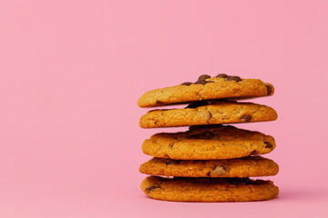 Stacked chocolate chip cookies against pink background