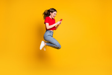 Full body photo of cheerful girl jump use smartphone discounts isolated over bright shine color...