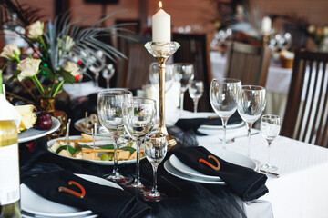 Close up of festive table setting with wine glasses, food and black napkins
