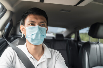 Asian businessman inside driving car automobile wearing protective surgical face mask protection from covid-19 coronavirus pandemic safety commuter traveling to work business travel social distancing