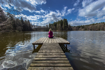 Beautiful young girl meditating by lake. Practicing yoga outdoors. Harmony and meditation concept.Healthy lifestyle. Woman feeling freedom and enjoying the nature.Workout in nature.Anti-stress therapy