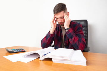Work stress. Office worker holding his head. Office worker stressed by overwork. Young man has a...