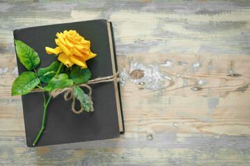 Bouquet of beautiful yellow roses and stack of old vintage books on wooden background. Copy space for nostalgic inscription.