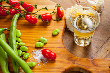 Assortment of beans and tomatoes with salt on a rustic wooden cutting board in natural light. Selective focus - shallow depth of field.