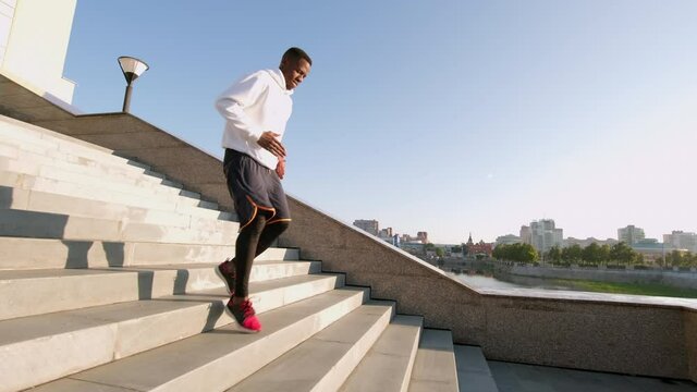 Full shot of african american athlete going down stairs doing cardio exercise at outdoor workout in daylight