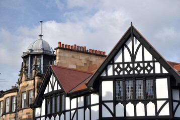 Fototapeta na wymiar Old Roofs-Cupola-Chimneys & Tudor Style Building against Blue Sky