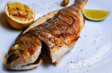 Delicious sea bass fish cooked on grill in seafood restaurant.Gourmet dorada fish grilled for...