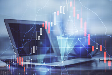 Stock market graph on background with desk and personal computer. Multi exposure. Concept of financial analysis.