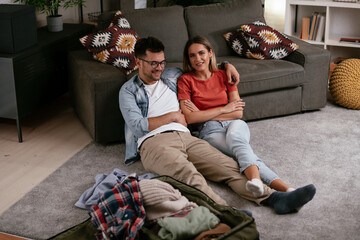 Obraz premium Loving couple packing clothes into travel bag. Boyfriend and girlfriend preparing for the trip.