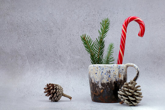 Christmas composition. Mug, pine branches, candy cane and pine cones on gray cement background. Home decor vintage style. Copy space