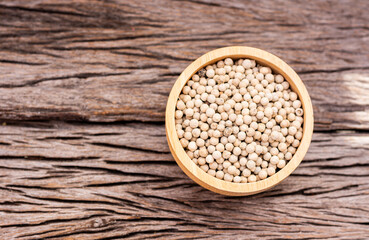 White peppercorns in a cup on a wooden table
