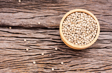 White peppercorns in a cup on a wooden table