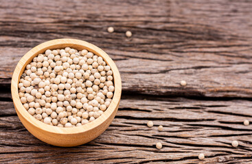 White peppercorns in a cup on a wooden table