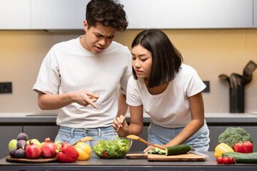 Asian Couple Learning To Cook Together In Modern Kitchen