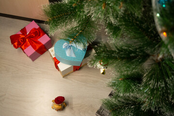 white, pink, blue heart-shaped gift box tied with a red ribbon, which stands on a gray painted box, next to a toy sheep in a red hat on a gray laminate. artificial tree branches. Christmas. copy space