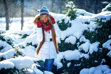Winter portrait of young beautiful blond woman wearing knitted snood covered in snow. Snowing...