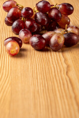 Top view of bunch of wet red grapes on wooden table, selective focus, vertical, with copy space