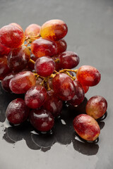Top view of bunch of wet red grapes on wet slate and reflection, selective focus, with back light, vertical