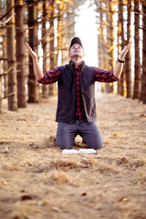 Vertical selective focus shot of a man praying in a forest