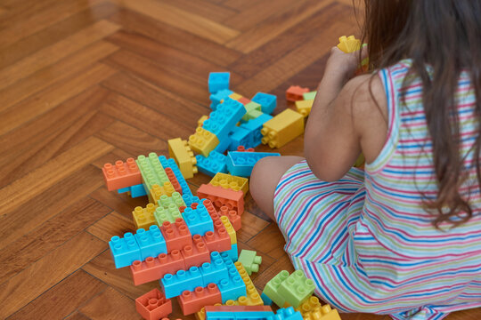 girl playing with blocks on the wooden floor in her room