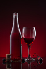Bottle and glass of Lambrusco wine  on red dark background.
