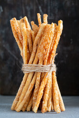 Vertical Stack of grissini breadsticks with cheese and crispy crust on a wooden table