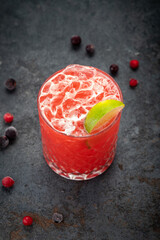 Berry cocktail with crushed ice, lime, mint and currant, on a dark table, selective focus, top view