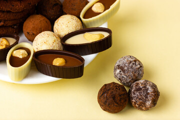 White plate with chocolates and truffles on a yellow background.