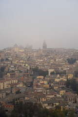 Fototapeta na wymiar Niebla sobre la ciudad de Toledo, España. Vista de la Catedral y barrio antiguo sobre el río Tajo.