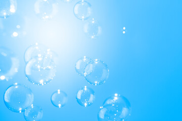 Abstract, Beautiful shiny transparent soap bubbles float on a blue texture background. Natural freshness summer holiday background.