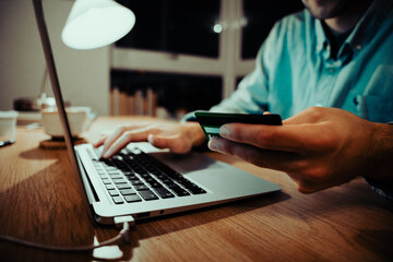Caucasian business man making online payment holding credit card typing on laptop sitting in apartment 