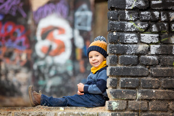 Child, posing in an old ruin building, sprayed with graffiti