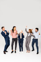 Fototapeta na wymiar Positive multicultural businesspeople showing yeah gesture on grey background