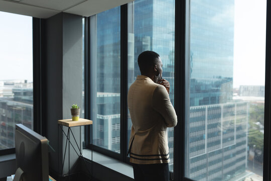 African american man wearing face mask looking out of window