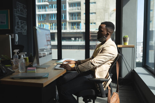 African american man with lowered face mask working in office