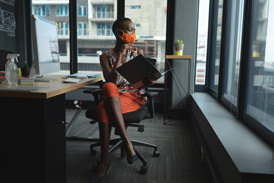 African american woman wearing face mask working in office