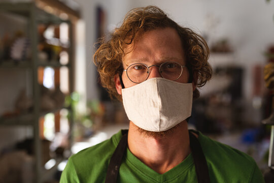 Portrait Of Caucasian Man Wearing Face Mask At Pottery Studio