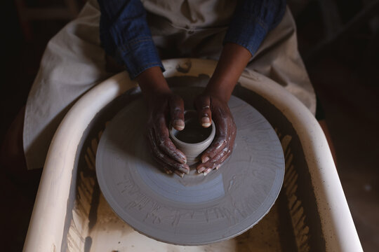Mixed race female potter in face mask working in pottery studio