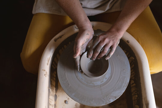Caucasian female potter in face mask working in pottery studio