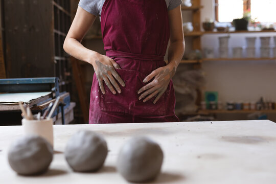 Caucasian female potter in face mask working in pottery studio
