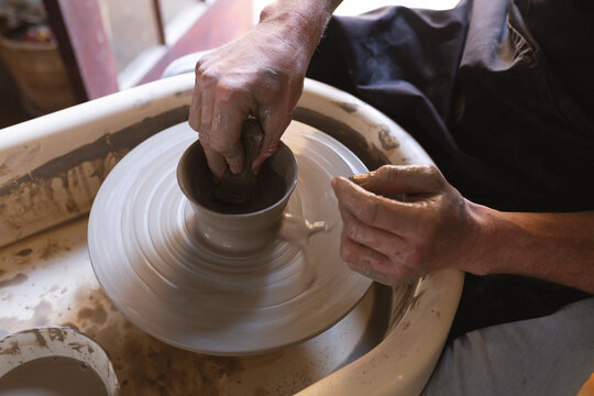 Caucasian male potter in face mask working in pottery studio