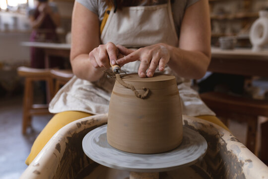 Caucasian female potter in face mask working in pottery studio
