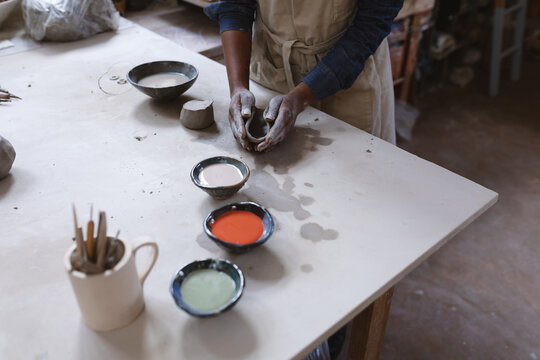 Mixed race female potter in face mask working in pottery studio