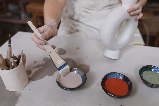Caucasian female potter in face mask working in pottery studio